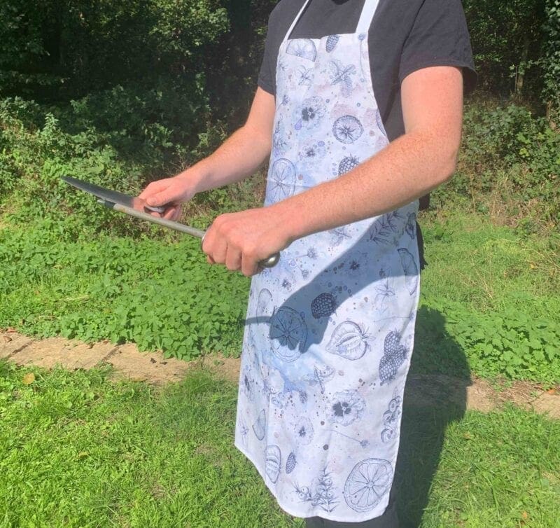 A man wearing an apron holding a knife.