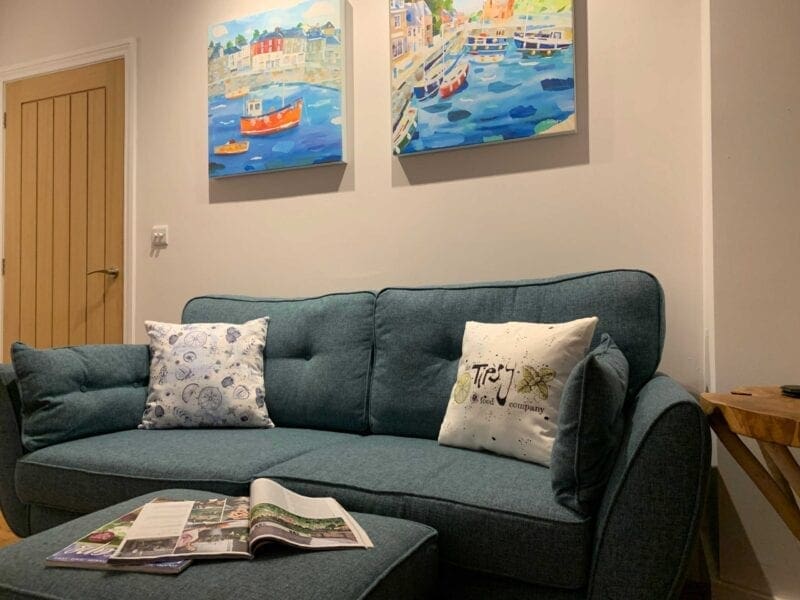 A living room with a blue couch and two paintings on the wall.