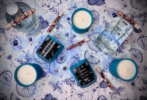 A set of candles and a bottle of water on a blue tablecloth.