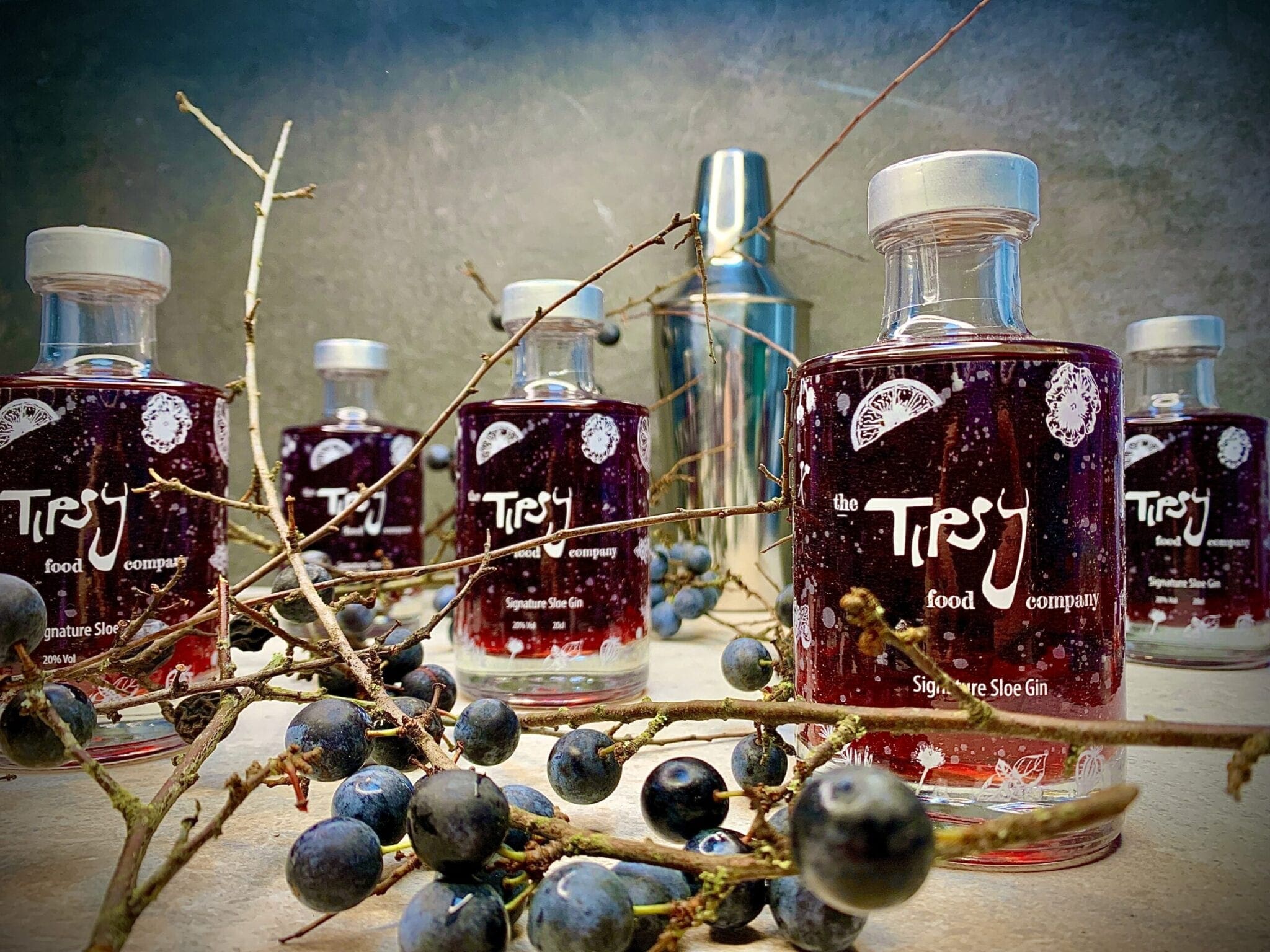 A group of bottles with grapes and berries on a table.