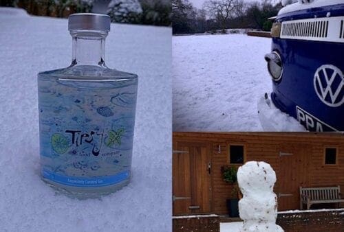 A snowman and a vw gin bottle in the snow.