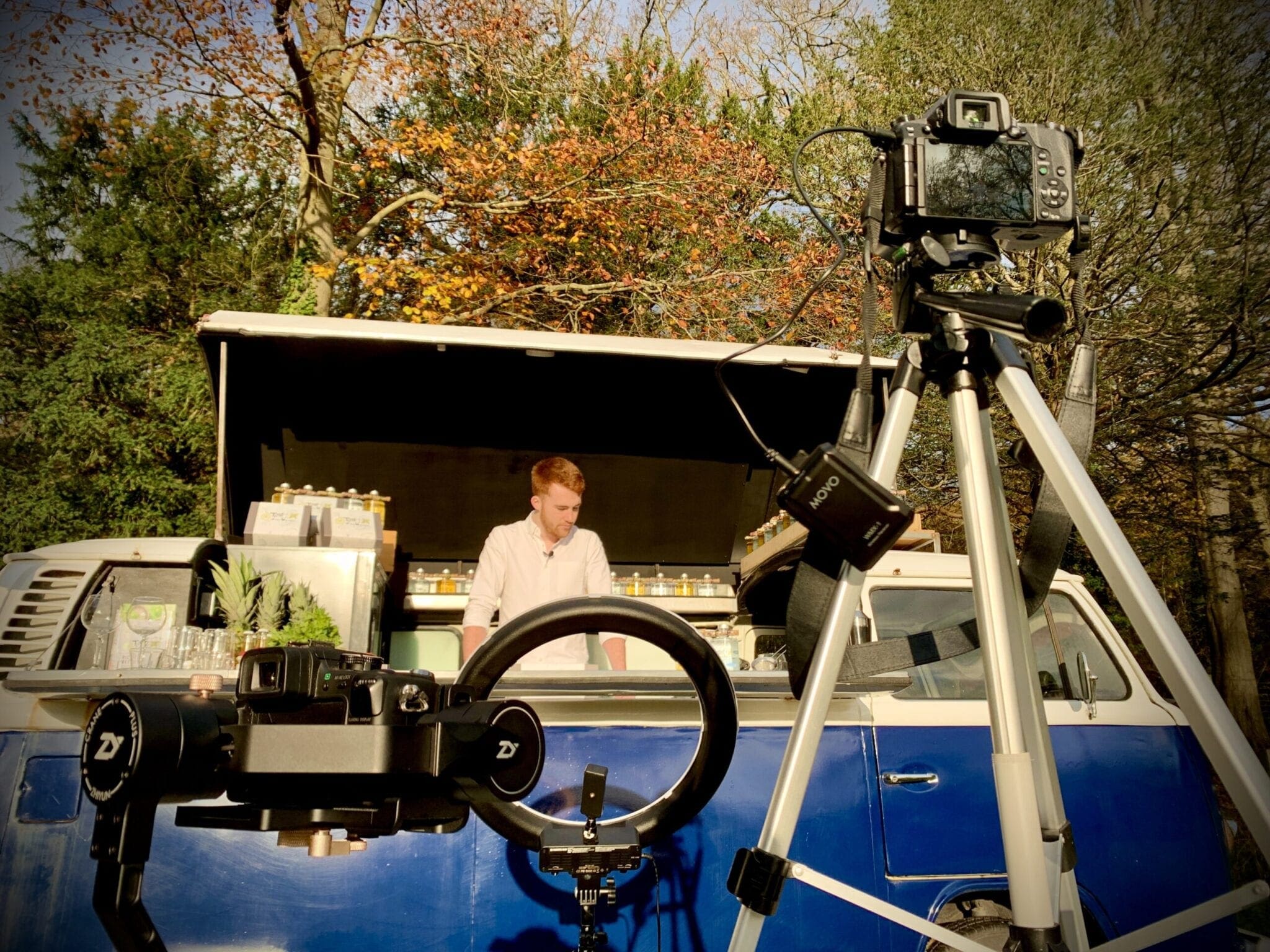 A man standing in front of a vw bus with a camera.