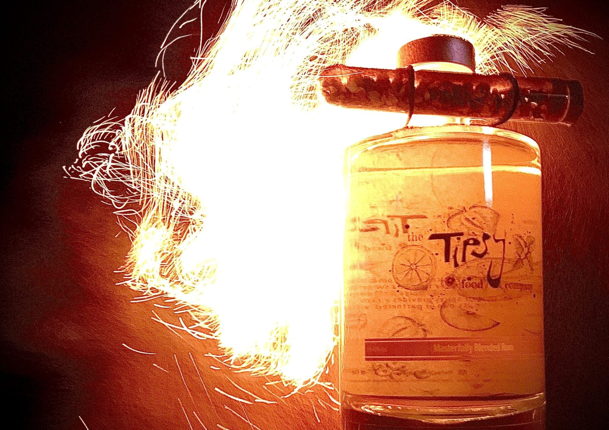 A bottle of liquor with fire coming out of it.