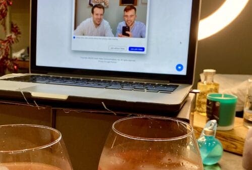 Two glasses of wine on a table next to a laptop.