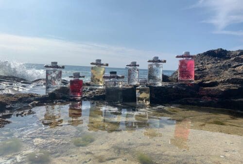 A group of bottles sitting on rocks near the ocean.