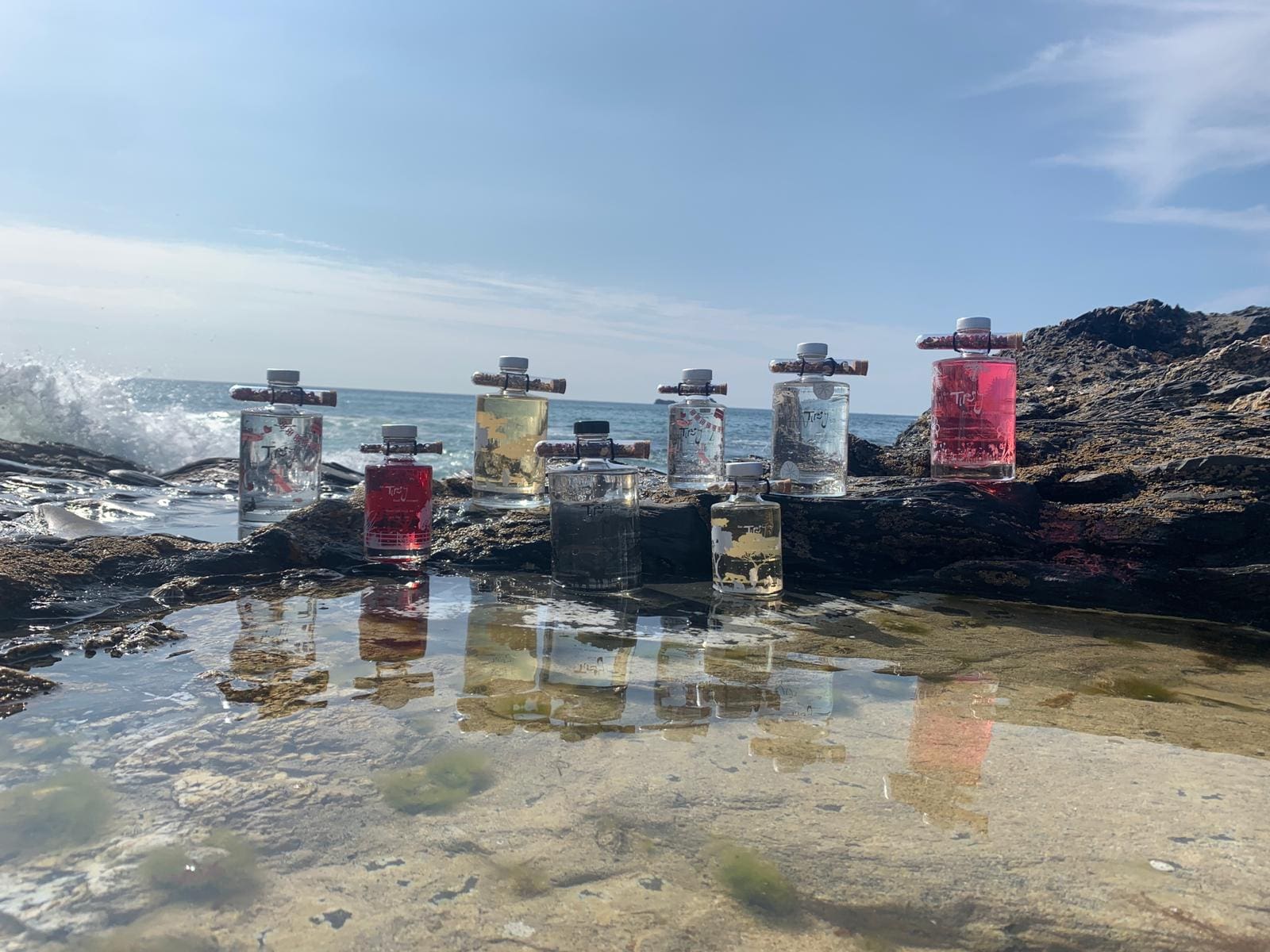 A group of bottles sitting on rocks near the ocean.