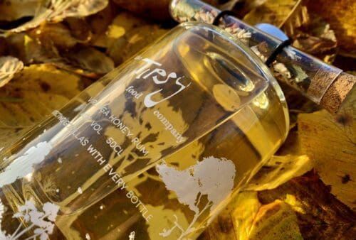 A bottle of perfume sitting on a pile of leaves.