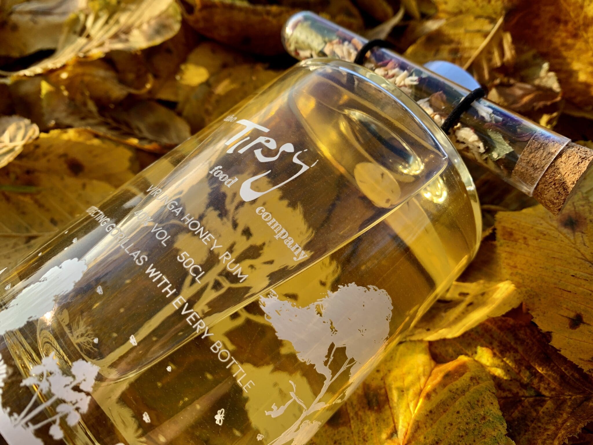 A bottle of perfume sitting on a pile of leaves.