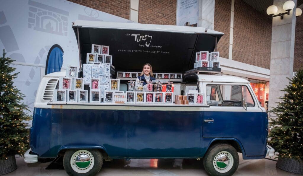 A woman is standing next to a blue vw bus.