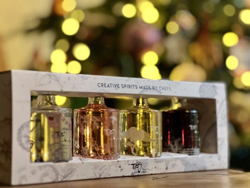 A box with three bottles of perfume in front of a christmas tree.
